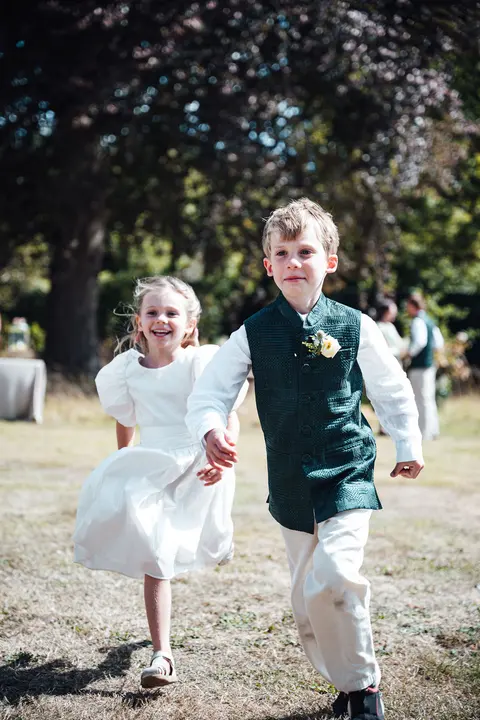 Two children running hand in hand across the lawn