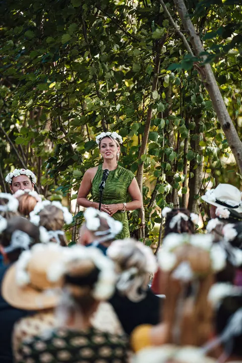 A guest in a flower crown standing among the seated guests