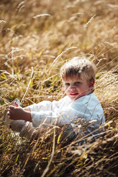 A boy laughing in the long grass