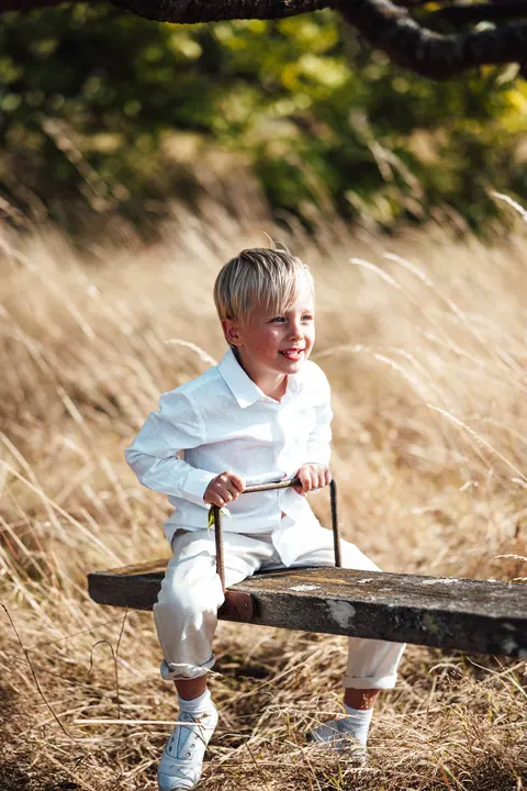 A boy standing in the long grass smiling