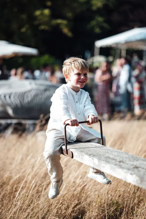 A boy on the seesaw with the party blurred behind him