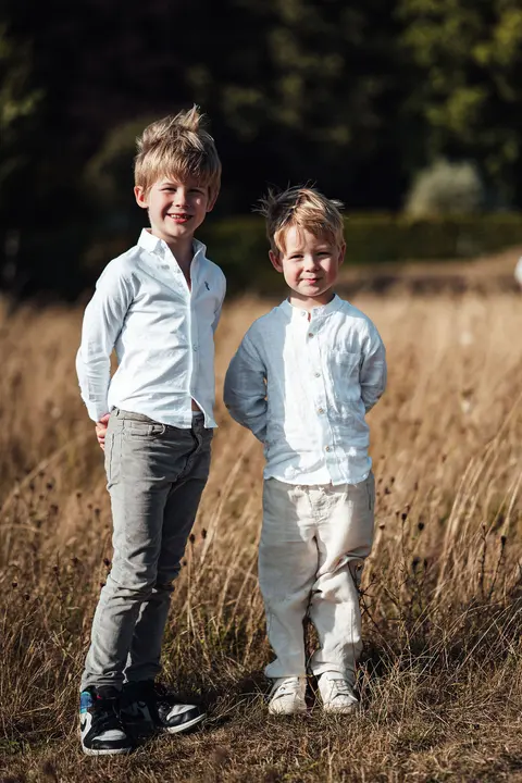 Two page boys in white shirts standing in the long grass