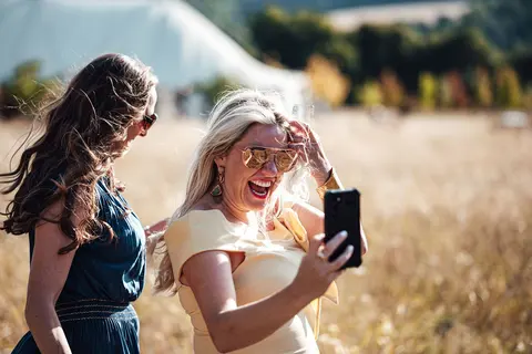 Two guests laughing together before taking a selfie