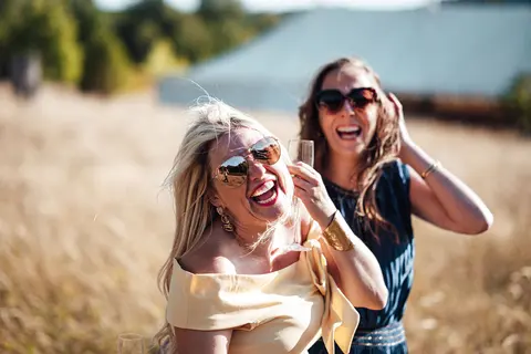 Two guests laughing and taking a selfie in the long grass