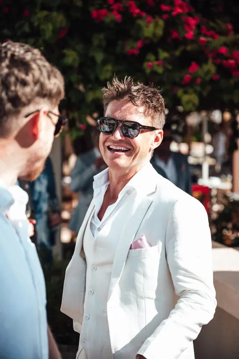 A guest in a white jacket laughing with a friend