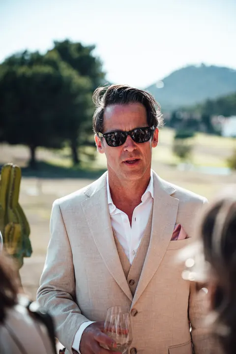 A guest in a tan waistcoat and sunglasses, in profile