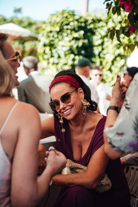 A guest in a red headscarf laughing in the crowd