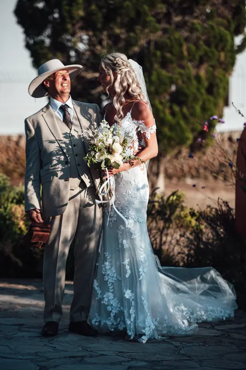 The bride arriving on the arm of a man in a white hat