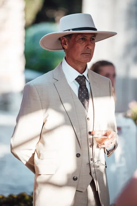 A guest in a wide brimmed hat and suit