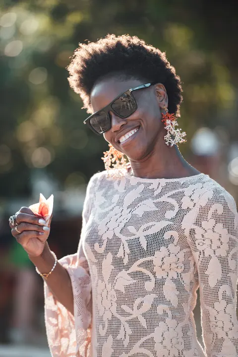A guest in lace and sunglasses laughing in warm light