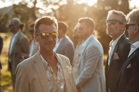 Guests in linen and sunglasses gathered in low sun