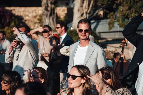 Guests cheering as the couple stand beneath the olive arch