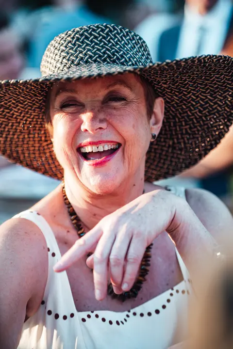 A guest in a woven hat laughing and pointing
