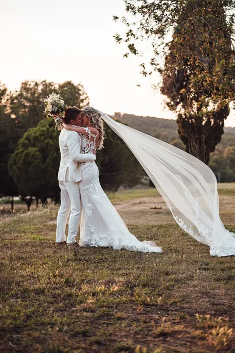 The couple embracing as the veil lifts in the wind