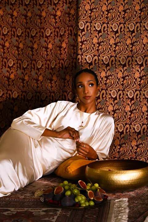 Model seated on the carpet beside the brass bowl of fruit