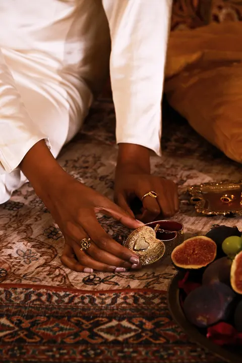 A hand picking an earring up from the patterned carpet