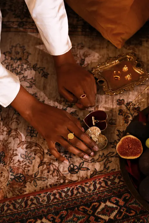 A hand reaching toward the brass bowl of figs