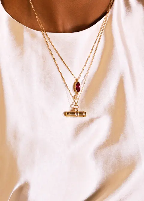 Close detail of a gold pendant necklace on ivory silk