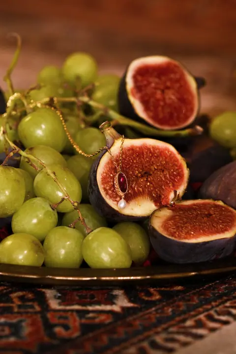 Halved figs and green grapes on a platter on a patterned carpet