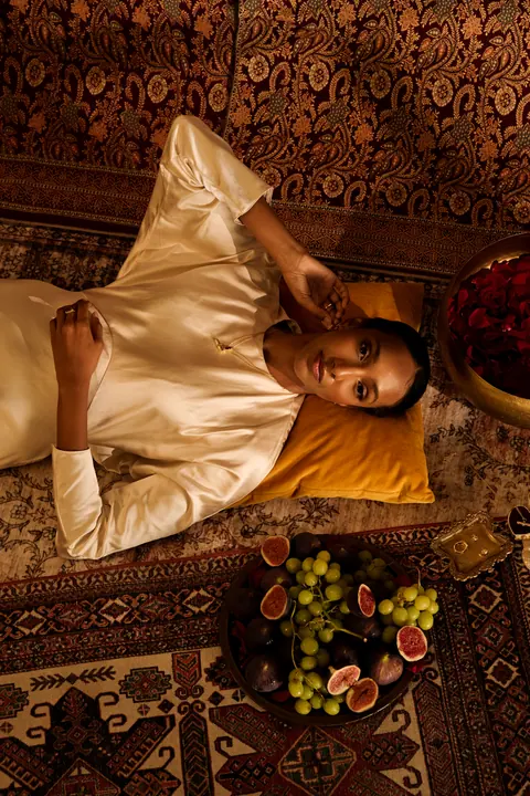 Model lying on cushions seen from above, surrounded by fruit