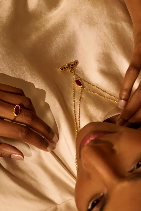 Overhead detail of a gold necklace and ring against ivory silk