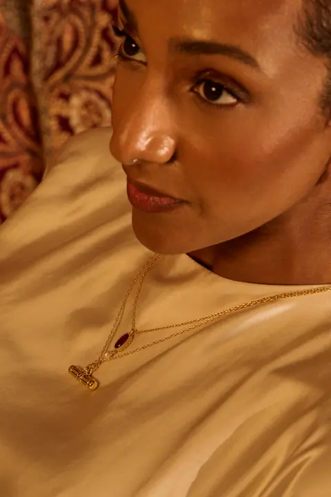 Model looking over her shoulder, a gold pendant catching the light