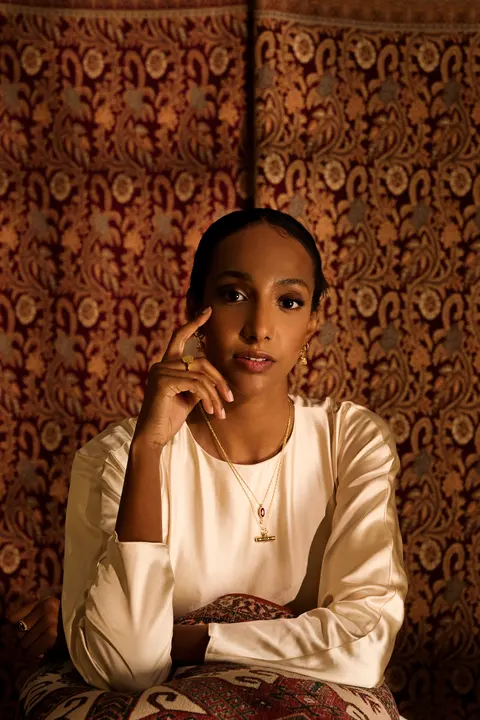 Model seated with her chin resting on her hand