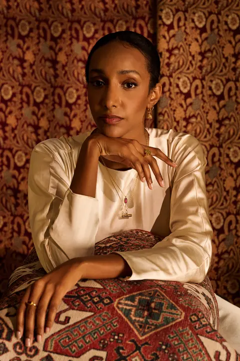 The same pose against the patterned wall hanging