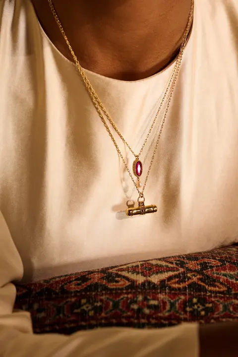 Layered gold necklaces resting on ivory silk