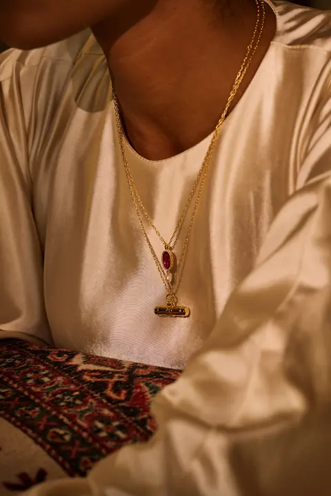 A single gold pendant on ivory silk, close detail