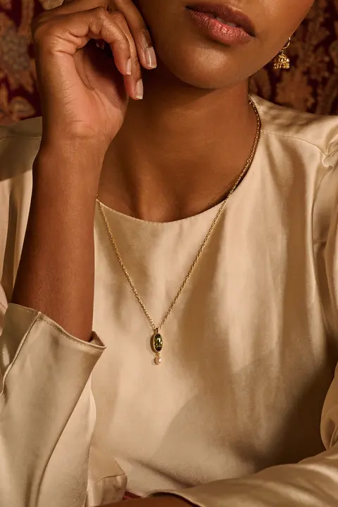Portrait with a hand raised to the face, pendant visible