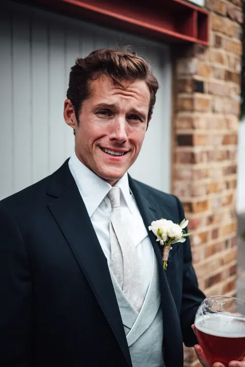 The groom with a buttonhole and a pint, smiling