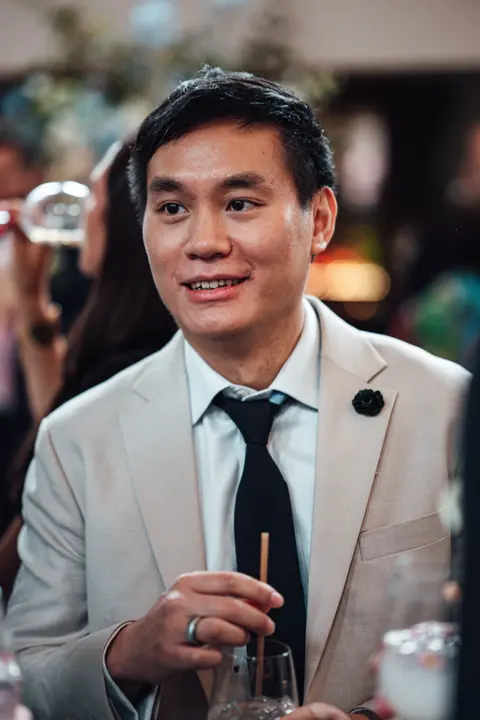 A guest in a cream jacket smiling with a drink