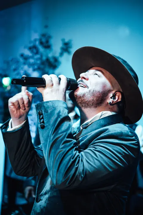 A singer in a hat performing under blue light