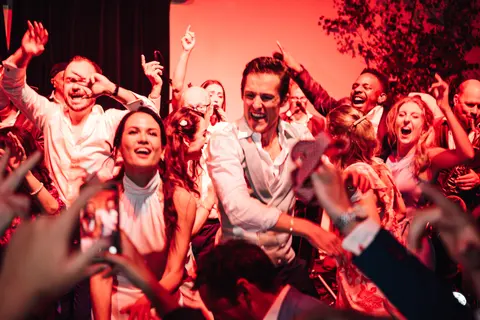 The dance floor in red light with guests mid jump