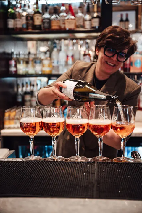A bartender pouring a row of pink spritzes