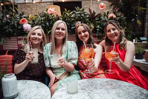 Four guests raising spritzes at a marble table