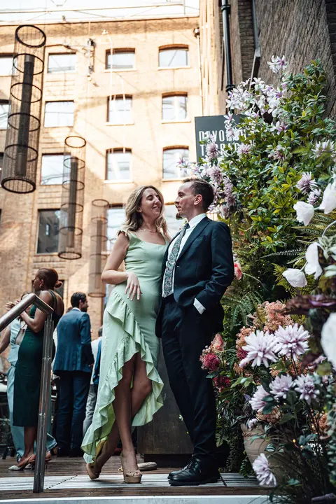 A guest in a green ruffled dress posing with a groomsman