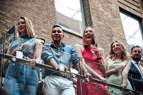 Guests leaning on a balcony rail, laughing