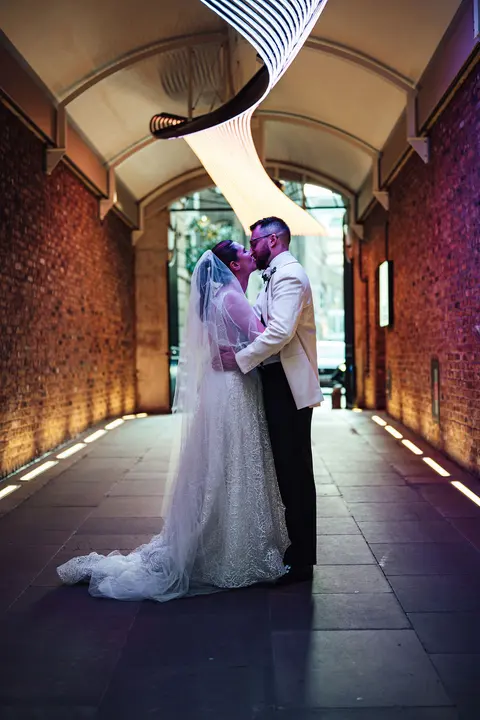 The couple kissing in a lit brick tunnel