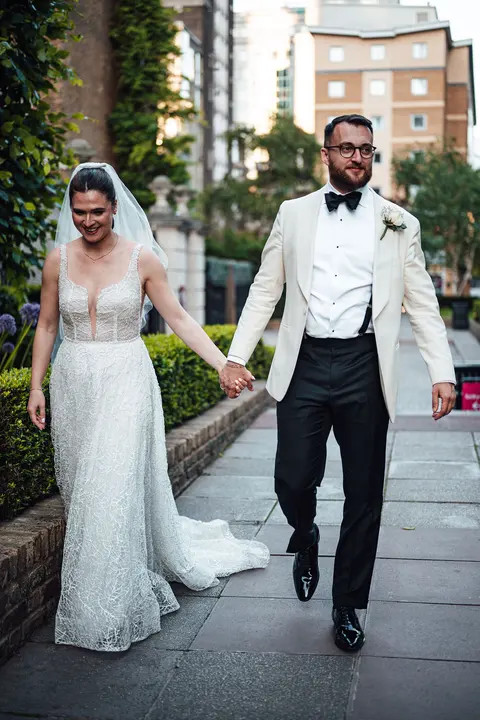 The couple walking hand in hand along a city pavement