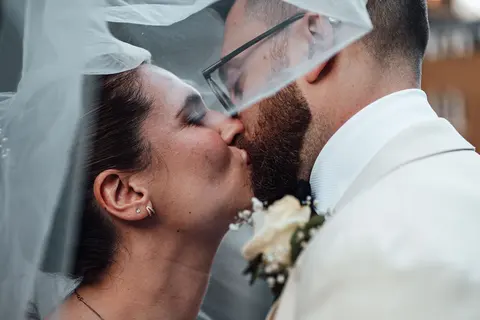 The couple close together under the veil