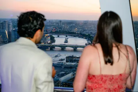 Two guests looking out over the Thames at sunset