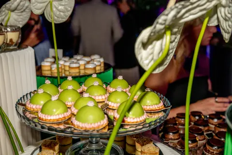 Green glazed tarts and desserts on a stand among anthurium flowers
