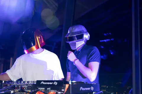 The DJs playing at the decks in blue and purple light