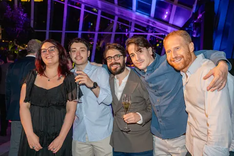 A group of guests posing together with drinks under purple light