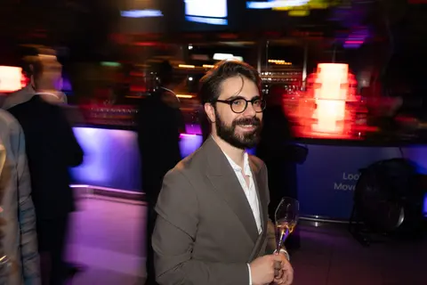 A guest with a glass of wine in purple light
