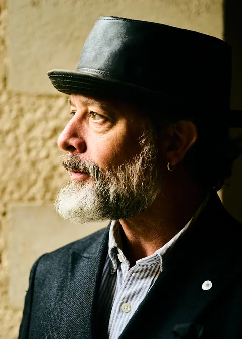 Profile of a bearded man in a hat in soft window light
