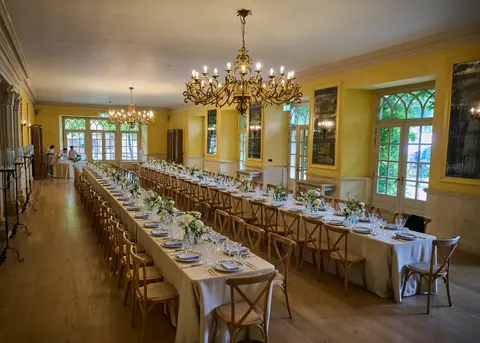 A long dining hall laid for lunch under crystal chandeliers