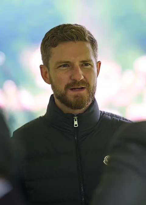 A guest in a green jacket mid conversation